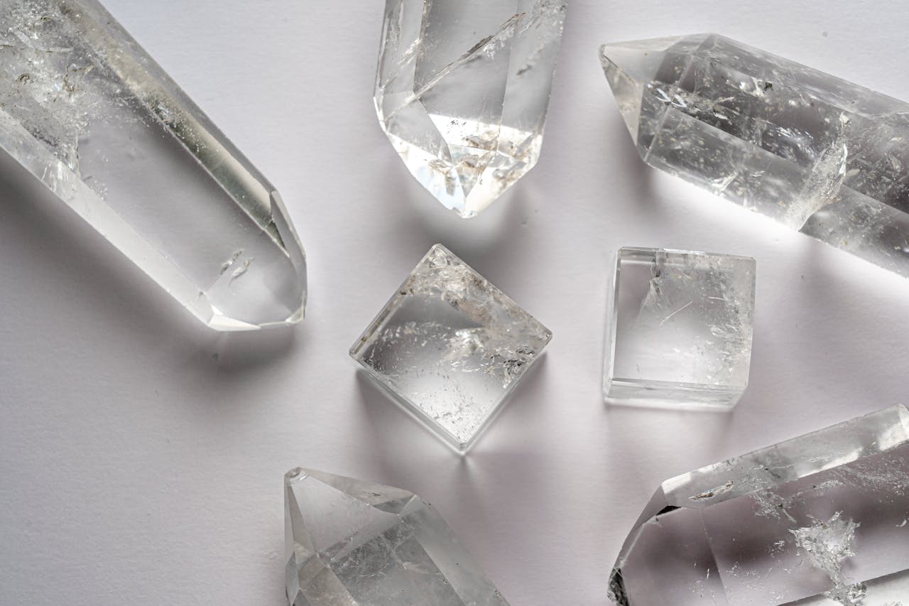 services-01 Detailed close-up of various quartz crystals arranged on a white surface.