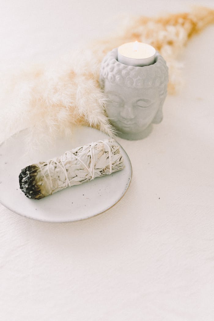 about-01 A serene arrangement featuring a sage bundle and candle for meditation in soft lighting.
